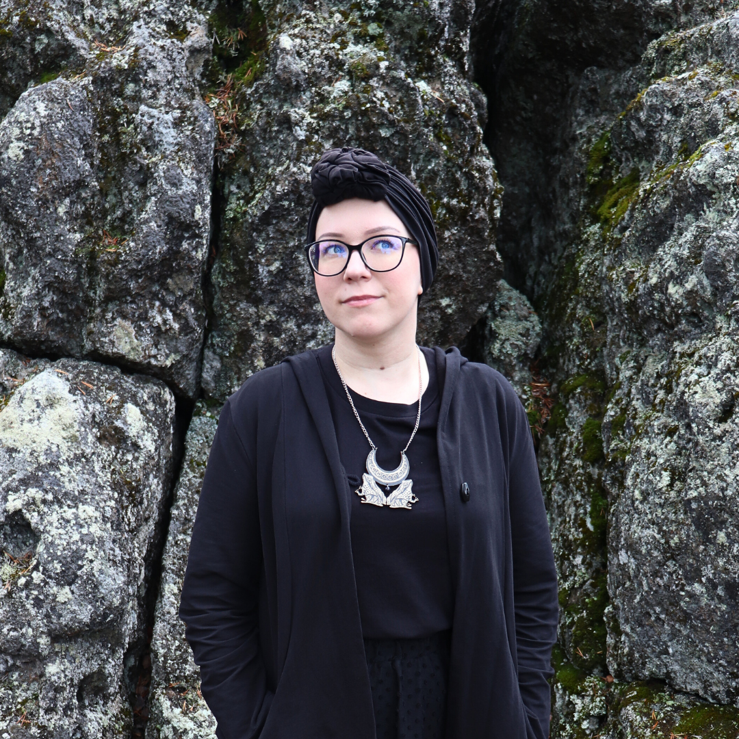 Nainen seisoo kalliota vasten.