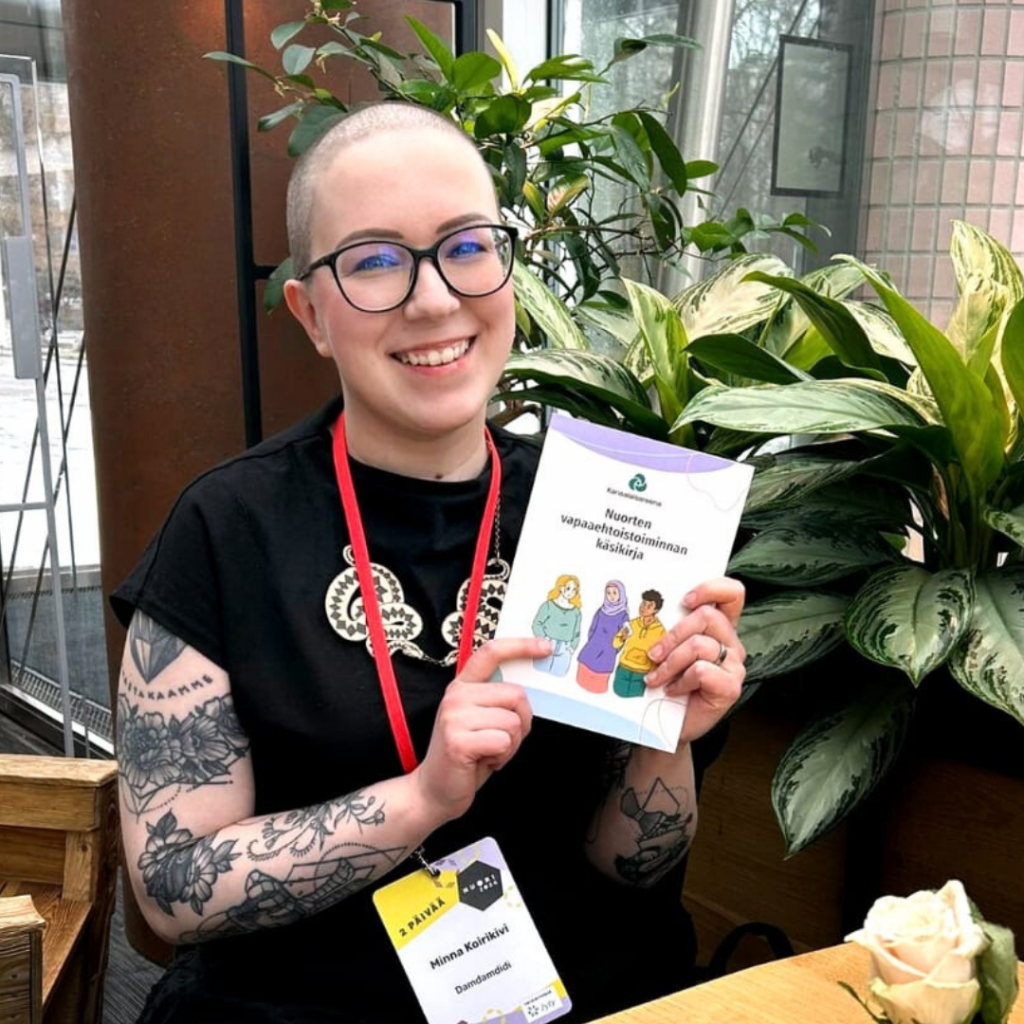 Nainen pitää kädessään nuorten vapaaehtoistoiminnan käsikirjan painettua versiota.